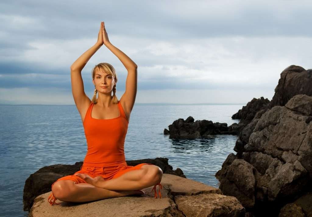 Beautiful young woman doing yoga exercise outdoors