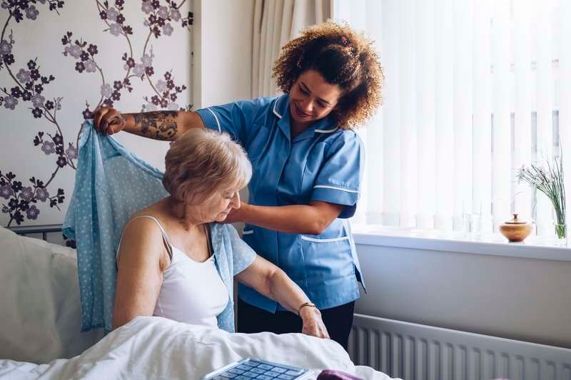 Home caregiver dressing senior