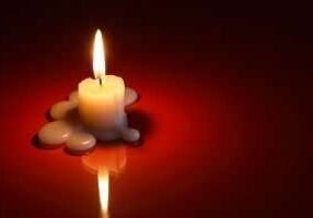 One lighting candle on dark background with free space for text