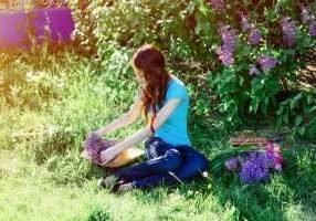 young woman sitting in the park on the grass with flowers of lilac and tulips